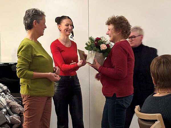 Person überreicht Blumen und Grußkarte