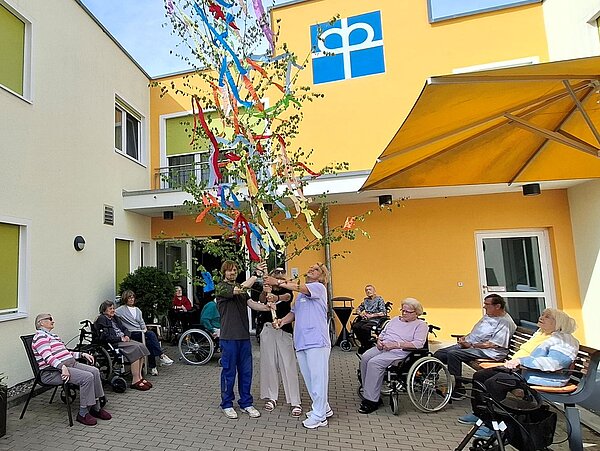 Maibaum mit Personen rundherum