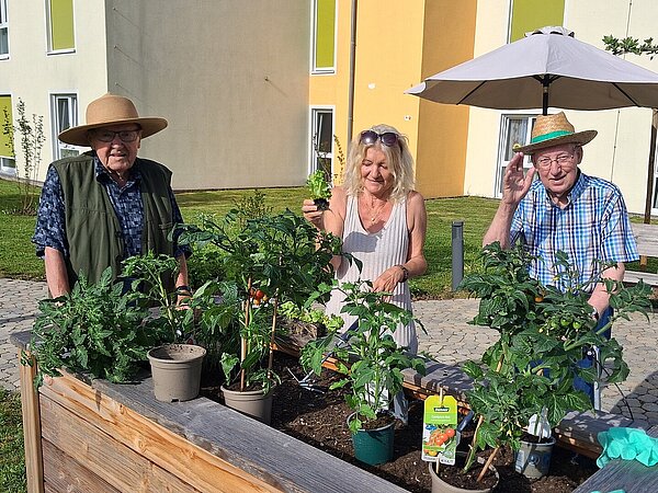 Personen stehen rund um ein Blumenbeet