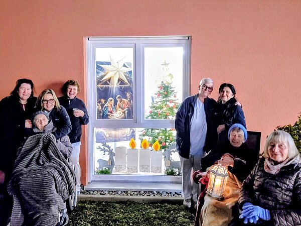 Personen vor einem weihnachtlich-geschmückten Fenster